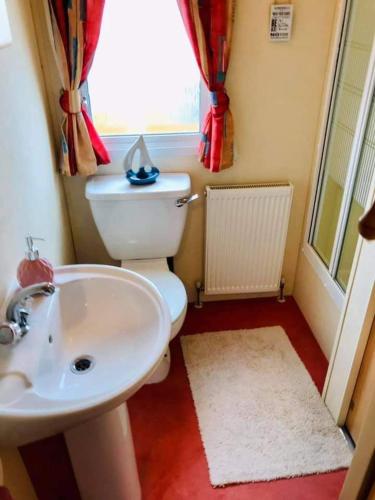 a bathroom with a toilet and a sink and a window at Seaside holidays the grange in Ingoldmells