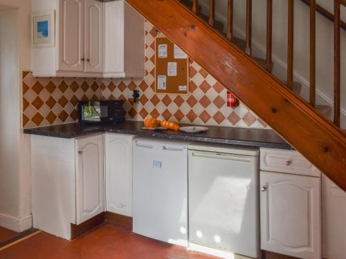 a kitchen with white cabinets and a staircase at Bishop Rock - Grl in Trevilley