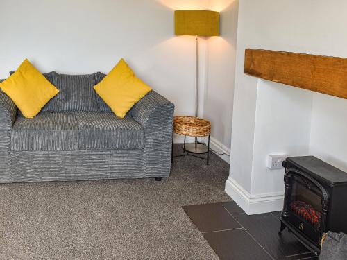 a living room with a gray couch with yellow pillows at Bryn Derwen in Harlech