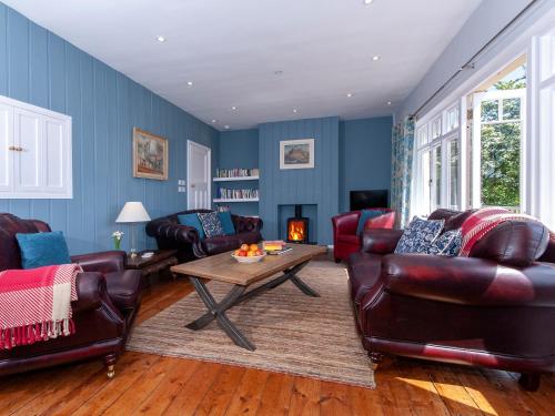 a living room with leather furniture and a table at Manorbier Boat House in Manorbier