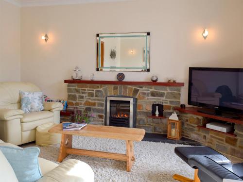 Una sala de estar con chimenea y televisión. en Yorke Villa, en Fishguard