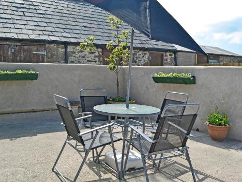 a table with four chairs and a table with a tree at Ty Main Cottage in Newborough