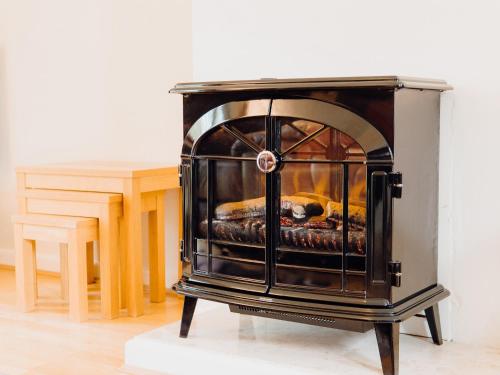 a stove sitting on a stand next to a table at Bosun's Cabin - Uk6719 in Lydstep