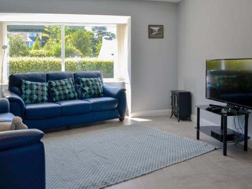 a living room with a blue couch and a tv at Rotherwood in Portinscale