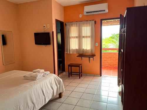 a bedroom with a bed and a tv and a window at Bela Vista in Canoa Quebrada