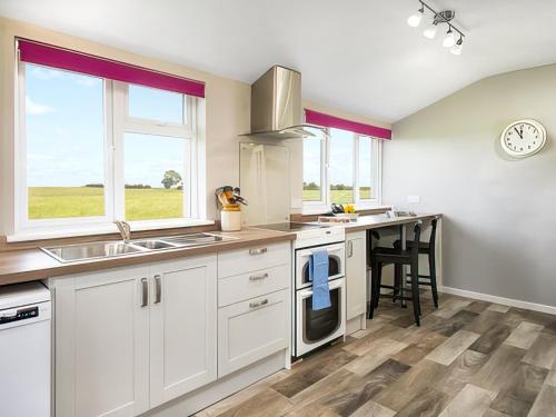 a kitchen with white cabinets and a sink and a table at Six The Square - Uk48869 in Belford