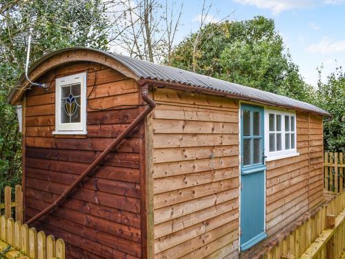 a log cabin with a gambrel roof and a blue door at Field View in St Austell