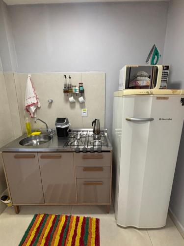 a small kitchen with a sink and a refrigerator at Loft funcional no centro! in Foz do Iguaçu