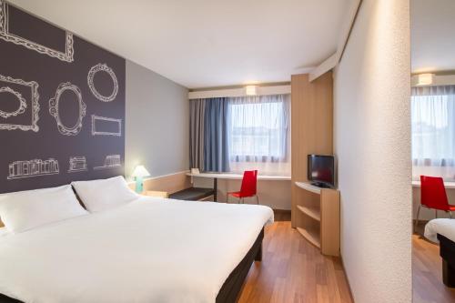 a hotel room with a large white bed and a desk at Ibis Szczecin Centrum in Szczecin