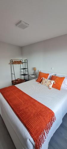 a bed with an orange and white blanket on it at Refúgio das Regadinhas in Santa Cruz