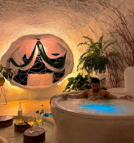 ein Mann in einer Badewanne in einem Zimmer in der Unterkunft Glamping CAVE in Isnos