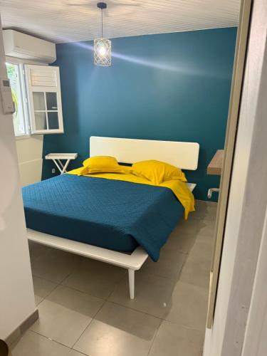 una habitación azul con una cama con sábanas amarillas en Petite Maison Contemporaine, en Rivière-Salée