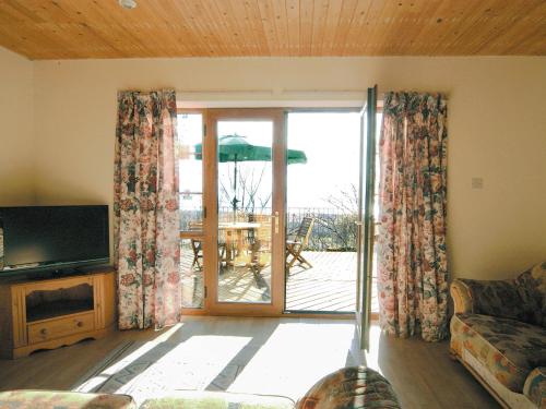 ein Wohnzimmer mit einer Couch und einer Glasschiebetür in der Unterkunft Seacrest Cottage - Hw7746 in Pendine