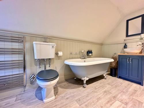 a bathroom with a tub and a toilet and a sink at The Barn at The Manor in Cole, Bruton in Cole