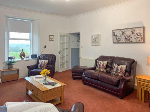 een woonkamer met 2 lederen stoelen en een salontafel bij Muirston Farmhouse - Uk44977 in Ochiltree