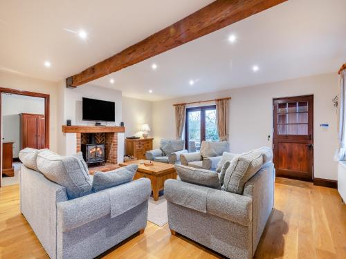 SculthorpeにあるWoodpecker Barn - Cwlの2つのソファと暖炉のあるリビングルーム