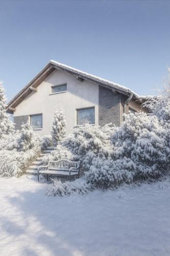 a snow covered house with a bench in front of it at U Králíčků in Vlcice