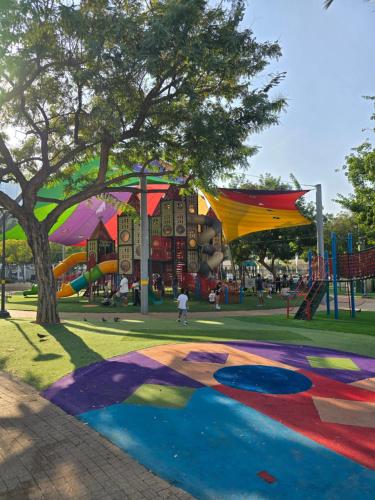 un parque con un parque infantil con un árbol y toboganes en מיני פנטהאוס נווה גן Mini Penthouse by Lake Neve Gan, en Petaj Tikva