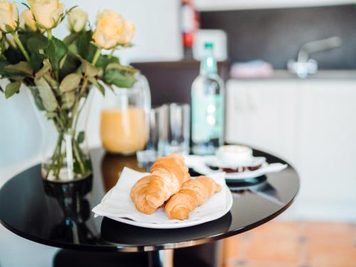 a table with a plate of croissants and a vase of roses at Gardener's Cottage - Uk6713 in Lydstep
