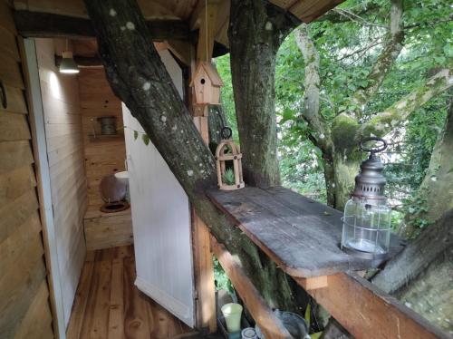 ein Baumhaus mit einer Bank und einer Laterne in der Unterkunft Maisonnette perchée au cœur de la nature in Allonnes