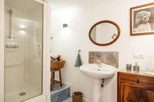 a white bathroom with a sink and a shower at Le Logis du Vieux Donjon in Châteaumur