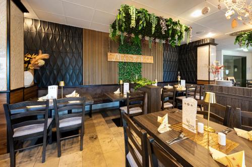 Un restaurante con mesas y sillas de madera y plantas. en ACHAT Hotel Leipzig Messe, en Leipzig