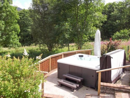 a hot tub sitting on a patio in a garden at Tigh Raineach in Strathyre