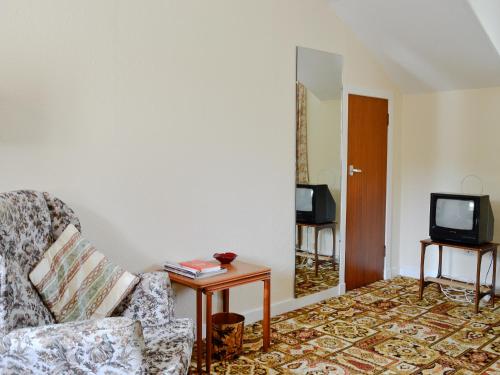 Una sala de estar con una silla y un televisor. en Lochnagar, en Largs