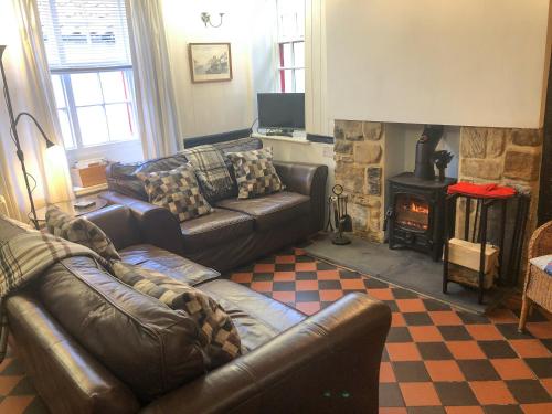 a living room with a leather couch and a fireplace at Castleton House in Staithes