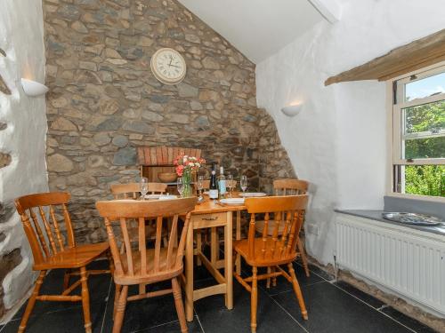 une salle à manger avec une table et des chaises en bois dans l'établissement Ffynnonddewi Farmhouse - Qc1535, à Llanhowell