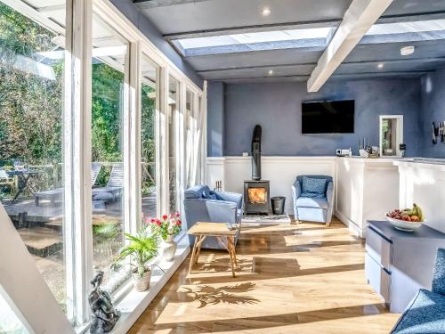 a conservatory with a living room with blue walls and windows at The Berm - Uk41199 in Llanfynydd
