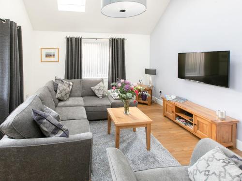 a living room with a couch and a tv at Rossie Cottage in Auchterarder