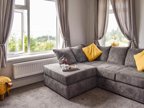 a living room with a couch and two windows at Bryn Derwen in Harlech