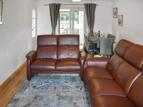 a living room with a brown leather couch and a table at Rowan Cottage in Northrepps