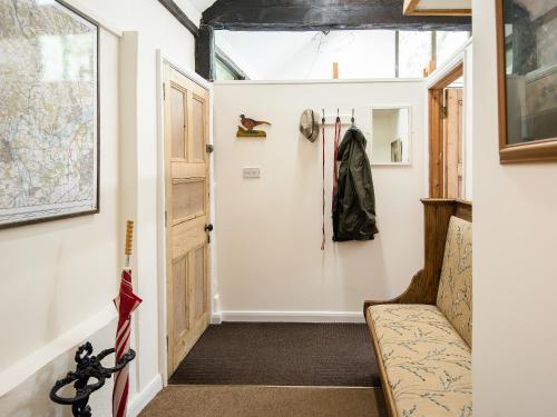 a hallway with a door and a coat hanging on a wall at Pheasants Hill Old Byre in Hambleden