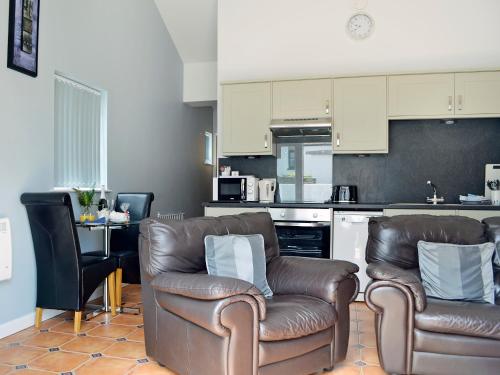 a living room with two chairs and a kitchen at Caddys Cottage - Uk6714 in Lydstep