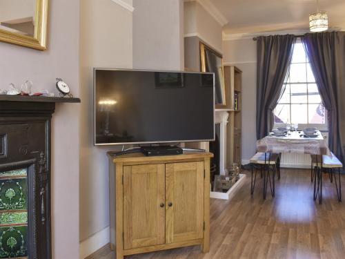 a large flat screen tv on a wooden stand in a living room at Divers Cottage in Herne Bay