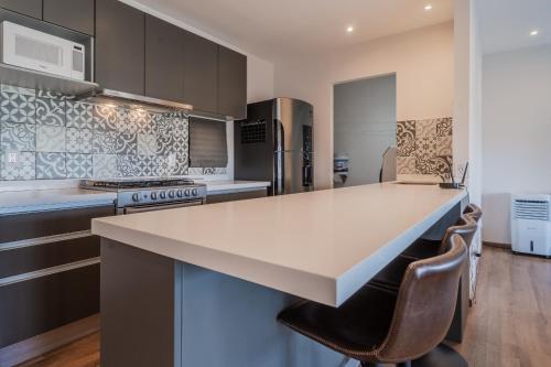 a kitchen with a large white counter top and chairs at Elegante apartamento 3 recamaras Juriquilla in Juriquilla