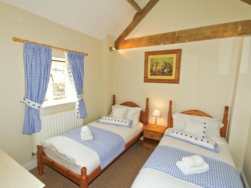 two twin beds in a room with a window at The Peacock Barn - E4713 in Dunstall