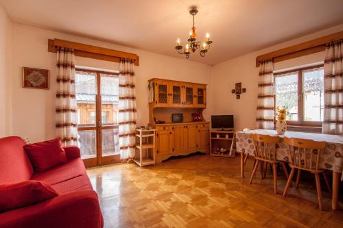 un soggiorno con un divano rosso e un tavolo di Appartamenti Sergio Benedetti a Sappada