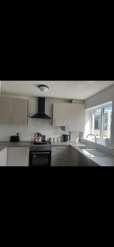 a kitchen with white cabinets and a sink and a window at Home away from home in Bury