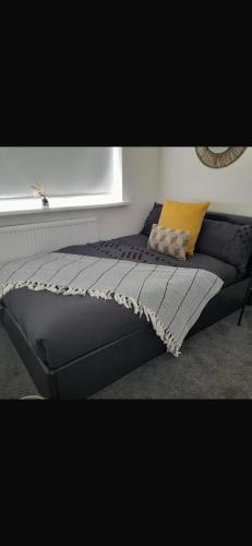 a bed sitting in a room with a window at Home away from home in Bury