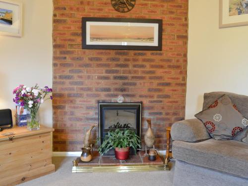 ein Wohnzimmer mit einer Ziegelwand und einem Kamin in der Unterkunft Ringstead Cottage in Ringstead