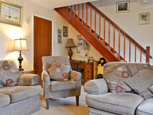 ein Wohnzimmer mit 2 Stühlen und einer Treppe in der Unterkunft Ringstead Cottage in Ringstead