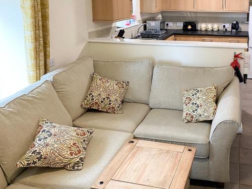 a living room with a couch with pillows and a table at Smithy Barn - Hw7592 in Bettws-yn-Rhôs