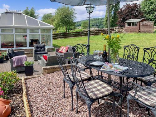 a patio with a table and chairs and a greenhouse at Keepsake View in Two Dales