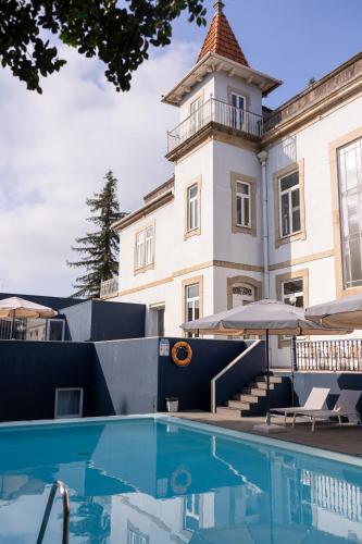 a building with a swimming pool in front of a building at Hotel Villa Garden Braga in Braga