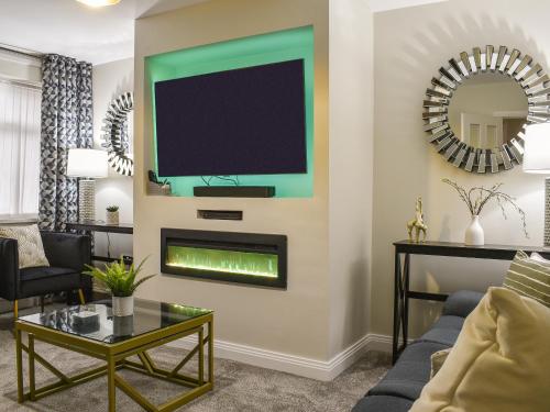 Una sala de estar con chimenea y un televisor en la pared. en Wharfdale Lodge, en Thornton
