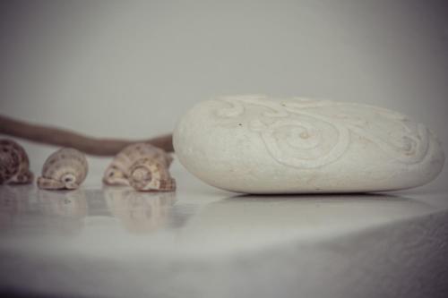 a white vase sitting next to some shells on a table at Sunhaus in Perissa