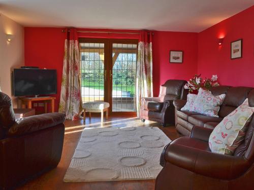 a living room with red walls and leather furniture at Celyn in Montgomery